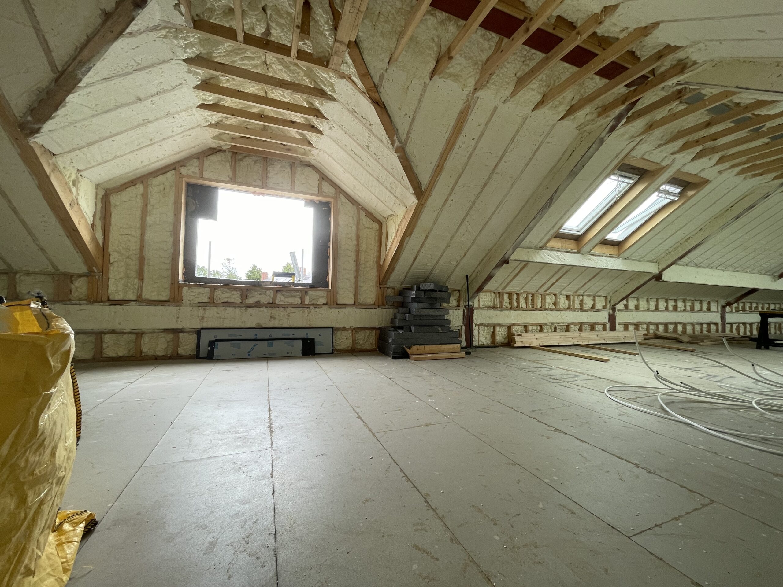 Close-up of spray foam insulation being applied to a roof, showcasing its soft, flexible texture and seamless coverage in filling gaps and crevices for enhanced energy efficiency.
